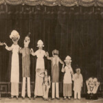 The whole troupe on stage, probably in Liverpool.
Olive Hart (nee Watts) presenting, John Henry Hart on tallest stilts. <br>
Photo courtesy of Victor Watts